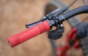 Primer plano de un puño rojo ReaFlex 6.0 en el manillar de una bicicleta, en el que se aprecian la palanca de freno, la palanca de cambios y parte del manillar negro Leatt Launch Control 6.0.
