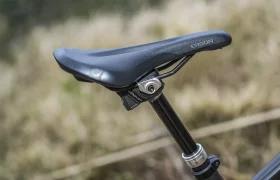 Primer plano de un sillín de bicicleta negro fijado a una tija telescópica inalámbrica RAGE Circuit, con un fondo exterior difuminado.