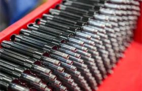 Primer plano de varios muelles metálicos negros con varillas brillantes dispuestos en filas paralelas en un contenedor rojo, parte de un envío de Sportmed distribución KS en España.