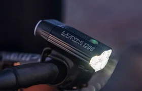 Un faro para bicicleta Lezyne React Drive 1200 con sistema Lezyne Radar React, montado en el manillar e iluminado en condiciones de poca luz.