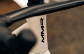 Primer plano de un cuadro de bicicleta MMR Aelion SL blanco con las letras negras "MMR" impresas verticalmente en él, destacando el elegante diseño de bici total.