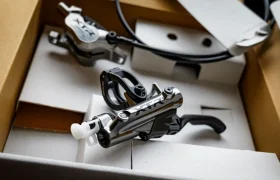 Vista en primer plano de las manetas de freno Shimano XTR para bicicletas de montaña y los componentes de los kits de actualización Shimano dentro de una caja de embalaje de cartón.