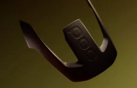 Se muestra un objeto negro y curvado con las letras «POC» grabadas en relieve —probablemente parte del casco integral POC Barocon Carbon— sobre un fondo con un degradado de amarillo oscuro y marrón, lo que evoca una sensación de aventura en descenso.