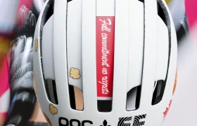 Ciclista con un casco POC blanco con varias pegatinas, entre ellas una roja en la que se lee «Total compromiso, sin resultados», montado en bicicleta.