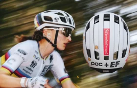 Un ciclista que lleva un casco blanco circula a gran velocidad; el casco, en el que se ve una pegatina roja con texto, también aparece en un primer plano aparte.