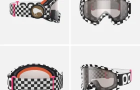Unas gafas de esquí con un diseño de tablero de ajedrez en blanco y negro, lentes transparentes, detalles rosas en la correa y el logotipo de un animal en la correa, similares en estilo a las gafas Ora de Robin Goomes, mostradas desde cuatro ángulos.