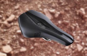 Un asiento de bicicleta negro con un diseño elegante se coloca sobre un fondo marrón borroso.