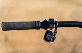 Primer plano de un manillar de bicicleta con empuñadura negra texturizada, botones de control electrónico Bosch de la potente serie Performance Line CX y fondo neutro difuminado.