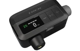 Un manómetro digital compacto, perfecto para el inflado de ruedas, con una pantalla que muestra "25" y "0 psi", botones etiquetados y el nombre de la marca "TREK" en la parte superior, compatible con la bomba eléctrica Trek Air Rush.
