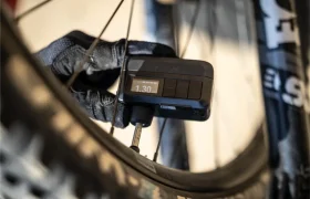 Una mano enguantada utiliza un manómetro digital Trek Air Rush para medir la presión de aire de un neumático de bicicleta, mostrando 1,30 en la pantalla.