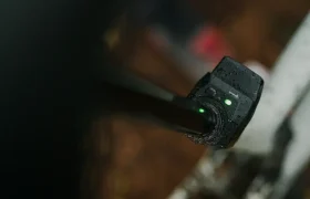 Primer plano de un cargador de bicicleta eléctrica húmedo conectado a una MTB, con una luz indicadora verde brillante.