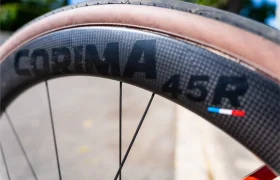 Primer plano de una rueda de bicicleta Ruedas Corima 45R que muestra la marca "CORIMA 45R" en una llanta de fibra de carbono, destacada por su ligereza y rendimiento, con un neumático y una pequeña pegatina roja, blanca y azul visibles.