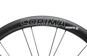 Primer plano de una llanta de bicicleta negra con el nombre de la marca "CORIMA" y el modelo "ESSENTIA 42" impresos, mostrando las Corima Essentia 42 ruedas carretera, ideales para carreras de resistencia.