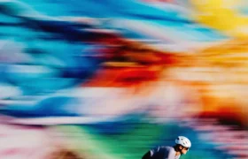 Un ciclista con casco pasa junto a un mural colorido y difuminado, haciendo gala de su velocidad con sus ruedas Zipp 404 S.