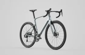 Una moderna bicicleta de carretera SCOTT Addict con manillar rebajado, frenos de disco y cuadro gris plateado sobre un fondo liso gris claro.