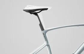 Primer plano de un cuadro de bicicleta SCOTT Addict blanco con sillín negro, con el logotipo de SCOTT en el tubo del sillín sobre un fondo gris liso.