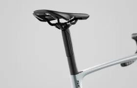 Primer plano de un sillín y una tija de sillín negros fijados a un cuadro de bicicleta SCOTT Addict de color claro sobre un fondo gris liso.