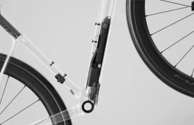 Primer plano de un cuadro transparente de bicicleta SCOTT Addict que revela un sistema de batería interno oculto, con cableado y piezas visibles cerca de las ruedas trasera y delantera.