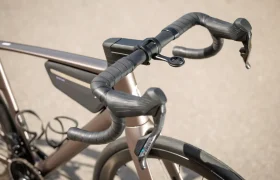 Primer plano del manillar de una moderna bicicleta de carretera SCOTT Addict, con cambios integrados, manillar aerodinámico, soporte para dispositivos montado en el manillar y bolsa de almacenamiento montada en el cuadro.