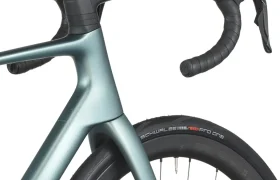 Primer plano de una moderna bicicleta de carretera SCOTT Addict que muestra el manillar, la rueda delantera y parte del cuadro en azul metálico, con una cubierta Schwalbe Pro One visible.