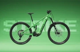 Una bicicleta de montaña eléctrica de doble suspensión SCOTT Strike 2027 de color verde, equipada con un potente motor Bosch CX, aparece en una vista de perfil sobre un fondo verde, con la palabra «SMILE» escrita en letras punteadas detrás de ella, lo que destaca tanto su rendimiento como su comodidad.