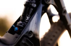 Primer plano del amortiguador de la suspensión trasera y el cuadro de una bicicleta de montaña, en el que se aprecian la marca FOX Float X y el mando de ajuste de la SCOTT Strike 2027, diseñada para ofrecer la máxima comodidad tanto en las subidas como en los descensos.
