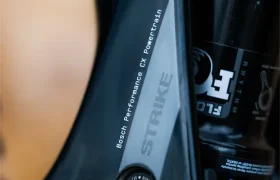 Primer plano de un cuadro negro de bicicleta de montaña SCOTT Strike 2027 con la inscripción «Strike» y equipado con el motor Bosch CX Performance Powertrain, en el que se aprecian parte de la suspensión y los componentes del sistema de propulsión, diseñados para ofrecer una mayor comodidad.