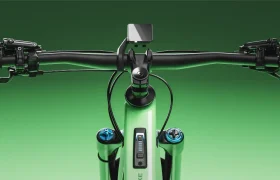 Primer plano del manillar de una bicicleta SCOTT Strike 2027 con pantalla digital y mandos, equipada con el potente motor Bosch CX para una mayor comodidad, sobre un fondo verde con degradado.