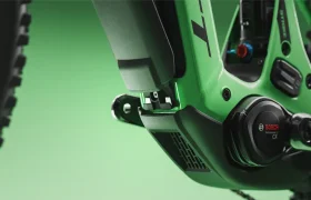 Primer plano del cuadro verde de una bicicleta eléctrica SCOTT Strike 2027, en el que destacan el motor Bosch CX Performance Line y el compartimento de la batería sobre un fondo verde, para ofrecer el máximo confort y estilo.