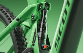 Primer plano del sistema de suspensión trasera de una bicicleta de montaña verde, en el que se aprecian la articulación, el amortiguador y parte del cuadro de la bicicleta, con la marca «SCOTT» visible. El modelo SCOTT Strike 2027 está diseñado para ofrecer un confort excepcional, garantizando que cada recorrido sea suave y controlado.