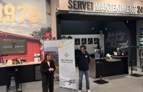Dos personas de pie cerca de un cartel Trek BCN Sud en una moderna tienda de bicicletas con áreas de servicio, una estación de café y bicicletas visibles en el fondo.