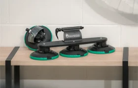 Una baca con ventosas Vic Sports con tres bases de ventosa de bordes verdes descansa sobre una mesa de madera contra una pared blanca.