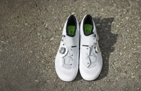 Un par de zapatillas de ciclismo Q36.5 Unique Pro con interiores negros y plantillas verdes se colocan una al lado de la otra sobre hormigón rugoso, reflejando un rendimiento de primer nivel para ciclistas dedicados.